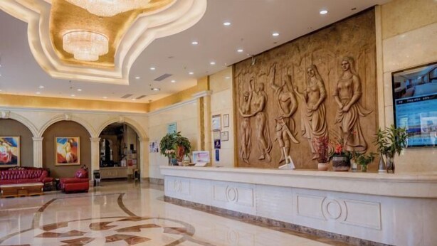 A lobby with a marble reception desk, a chandelier, and a wall with bas-relief sculptures.