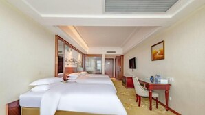 A hotel room with a large bed, a desk with a chair, a TV, and a painting on the wall.
