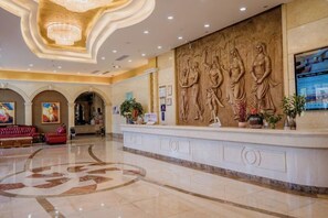 A hotel lobby with a reception desk, a large chandelier, and a wall with sculptural reliefs. - Shenzhen Aitingbao Hotel (Shenzhen)