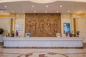 A reception area with a marble counter, a large wall sculpture, and framed pictures. - Shenzhen Aitingbao Hotel (Shenzhen)