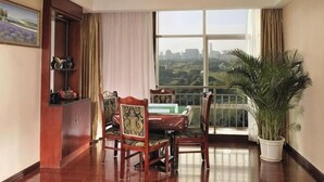 A dining area with a table and chairs, a potted plant, and a view of a cityscape through large windows.