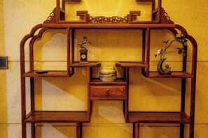 Un expositor de madera con estantes, un reloj y objetos decorativos.