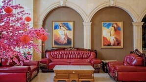 A room with a red leather sofa, a wooden coffee table, and two paintings on the wall.