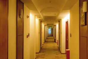 A hotel hallway with doors on both sides, carpeted flooring, and a ceiling light fixture. - Shenzhen Aitingbao Hotel (Shenzhen)