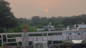 A rooftop terrace with a concrete floor, potted plants, and a white railing. - Osho cottage  (Rajnagar)