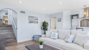 Un salon moderne avec un canapé, une table basse et un escalier menant à une autre pièce.