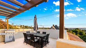 Une terrasse extérieure équipée d’un barbecue, d’une table à manger et de chaises.