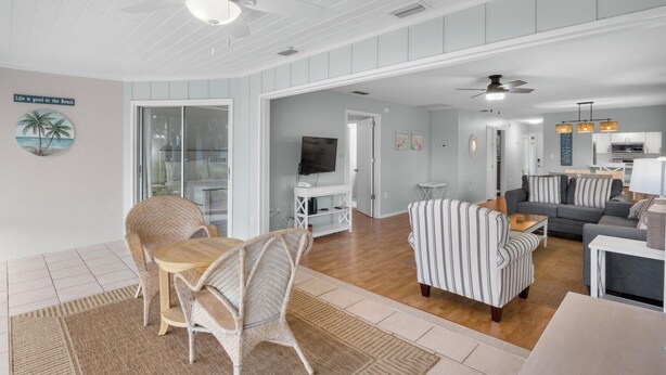 A spacious living room with a dining area, a kitchen, and a TV in the background. - Beachy Butterfly! Poolside Holmes Beach Stay! (Holmes Beach)