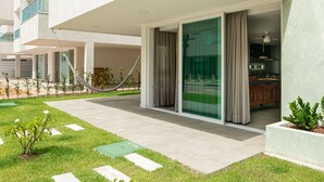 Een modern gebouw met een overdekt buitengebied, een hangmat en uitzicht op het interieur.