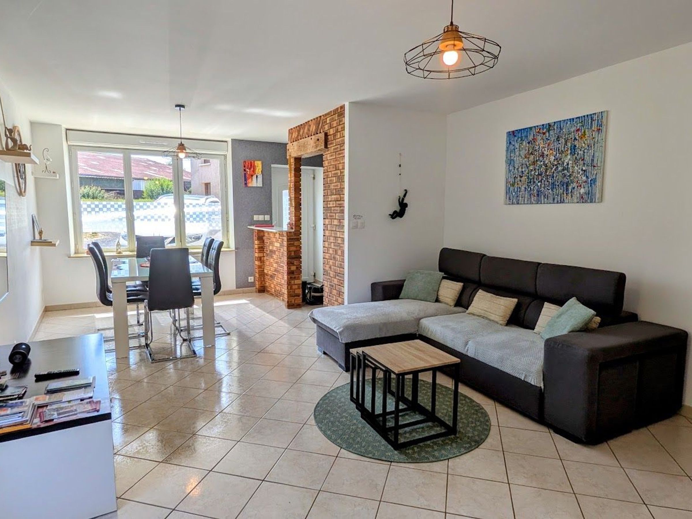 A modern living room with a sectional sofa, a small coffee table, and a dining area with chairs and a table.
