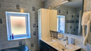 Une salle de bain moderne avec une baignoire, un meuble-lavabo à deux vasques, un grand miroir et une fenêtre donnant sur un beau paysage.