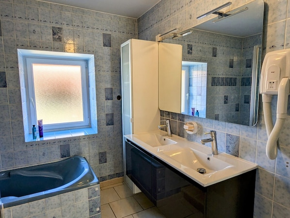 Un baño moderno con bañera, tocador doble, espejo grande y ventana con vistas.