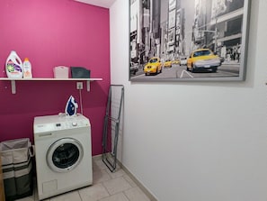 A laundry room with a washing machine, a drying rack, and a shelf with cleaning products. - Single-storey house with enclosed garden in Longchamps (Longchamps-sur-Aire)