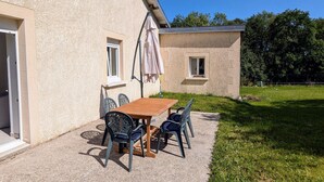 Une terrasse avec une table et des chaises, une petite fenêtre et une porte.
