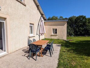 Un patio con mesa y sillas, un ventanal pequeño y una puerta.