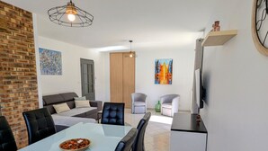 Ein modernes Wohnzimmer mit Essbereich, Kamin und Wand-Fernseher.