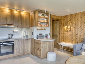 Una cocina moderna con muebles de madera, horno empotrado y encimera con cafetera y tostadora.