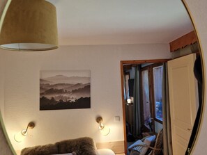 Quarto com cama, luminária na parede e quadro de paisagem.
