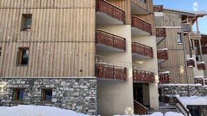 Un immeuble à plusieurs étages, doté de balcons en bois et d’un rez-de-chaussée en pierre.