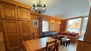 Un intérieur chaleureux, avec des éléments en bois, comprenant une table à manger, des chaises, un canapé et une cheminée.