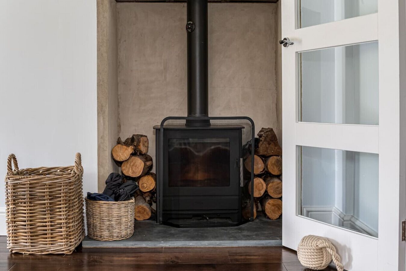 A cozy room with a wood-burning stove, a wicker basket, and a stack of firewood.