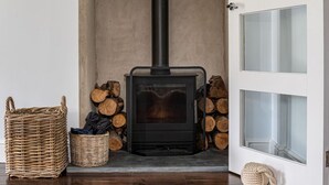 Une pièce chaleureuse avec un poêle à bois, un panier en osier et une pile de bois de chauffage.