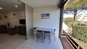 Ein Balkon mit Esstisch und Stühlen, einem Fernseher und einem Gemälde.
