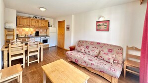 A compact living space with a kitchenette, a sofa, a dining table with chairs, and a bench.