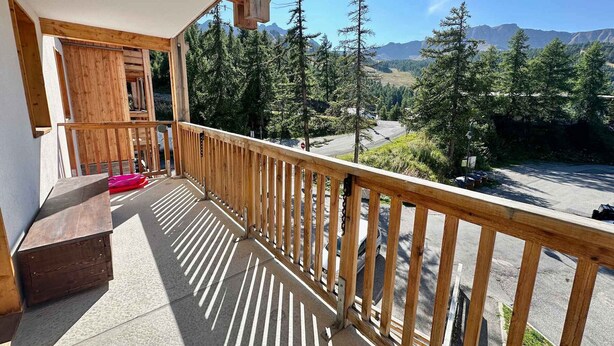 A wooden balcony with a view of a mountainous landscape.