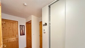 A hallway with wooden doors, a framed picture on the wall, and a thermostat.