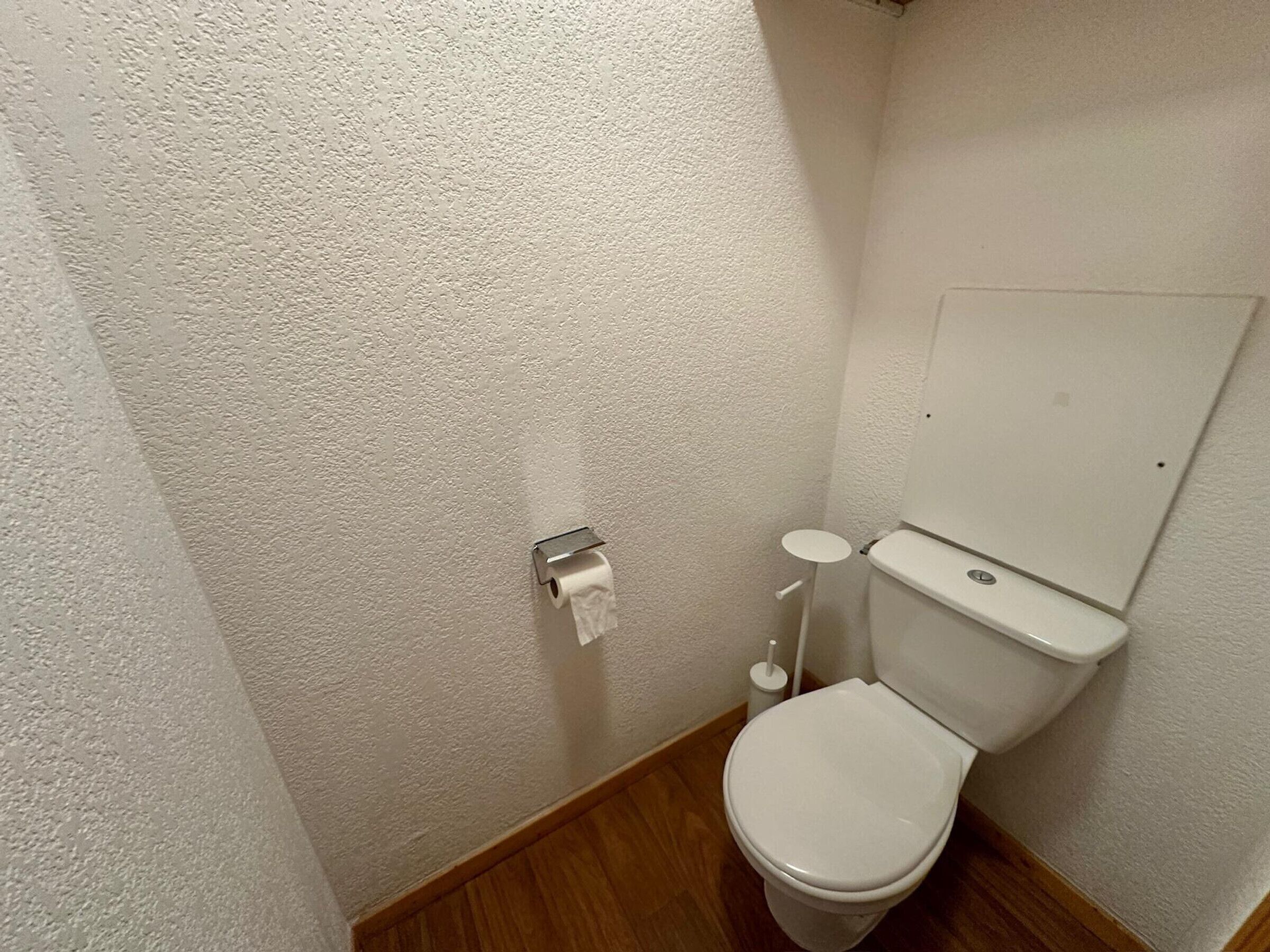 A small, compact bathroom with a toilet, a toilet paper holder, and a bidet.