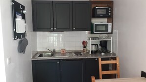 A compact kitchen with dark cabinets, a microwave, a coffee maker, and a sink.