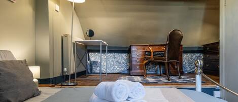 A hotel room with a bed, a desk, a chair, a dresser, and a lamp.