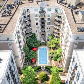 Ein mehrstöckiges Wohngebäude mit Innenhof, der einen Pool, Balkone und Grünflächen umfasst.