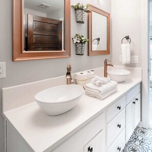 A modern bathroom with a large mirror, two sinks, and a wooden vanity. - Mad Hatter 2BR | Sauna, Pool, & Sky Lounge (Charlotte)