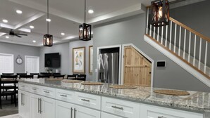 A spacious kitchen with white cabinetry, granite countertops, and hanging pendant lights. - Caton Manor Estate and Pool (Catonsville)