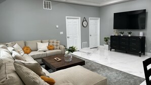 A modern living room with a sectional sofa, a coffee table, a TV, and a black cabinet. - Caton Manor Estate and Pool (Catonsville)