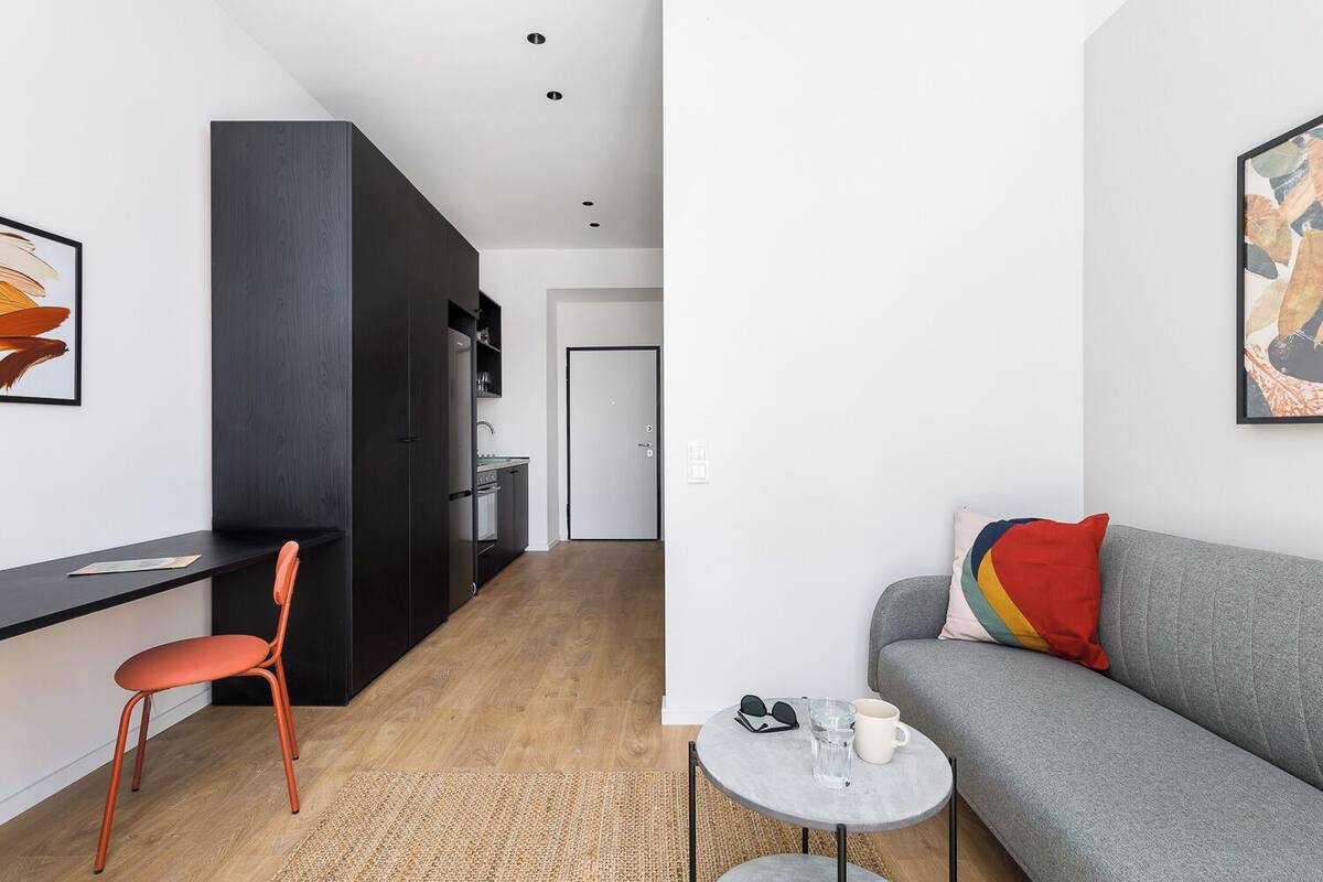 A modern living room with a grey sofa, a small round table, and a red chair.
