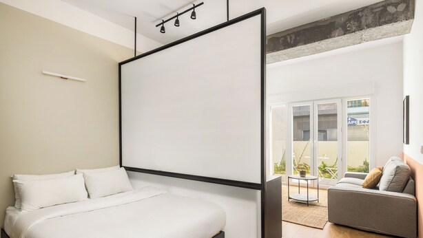 A bedroom with a bed, a sofa, and a sliding door to a balcony. - Soho Residence by halu! (Thessaloniki)