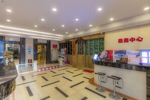 A hotel reception area with a reception desk, a waiting area with chairs, and a decorative wall with a sign. - Jin Yu Hotel (Zhuhai Gongbei Port Pedestrian Street) (Zhuhai)