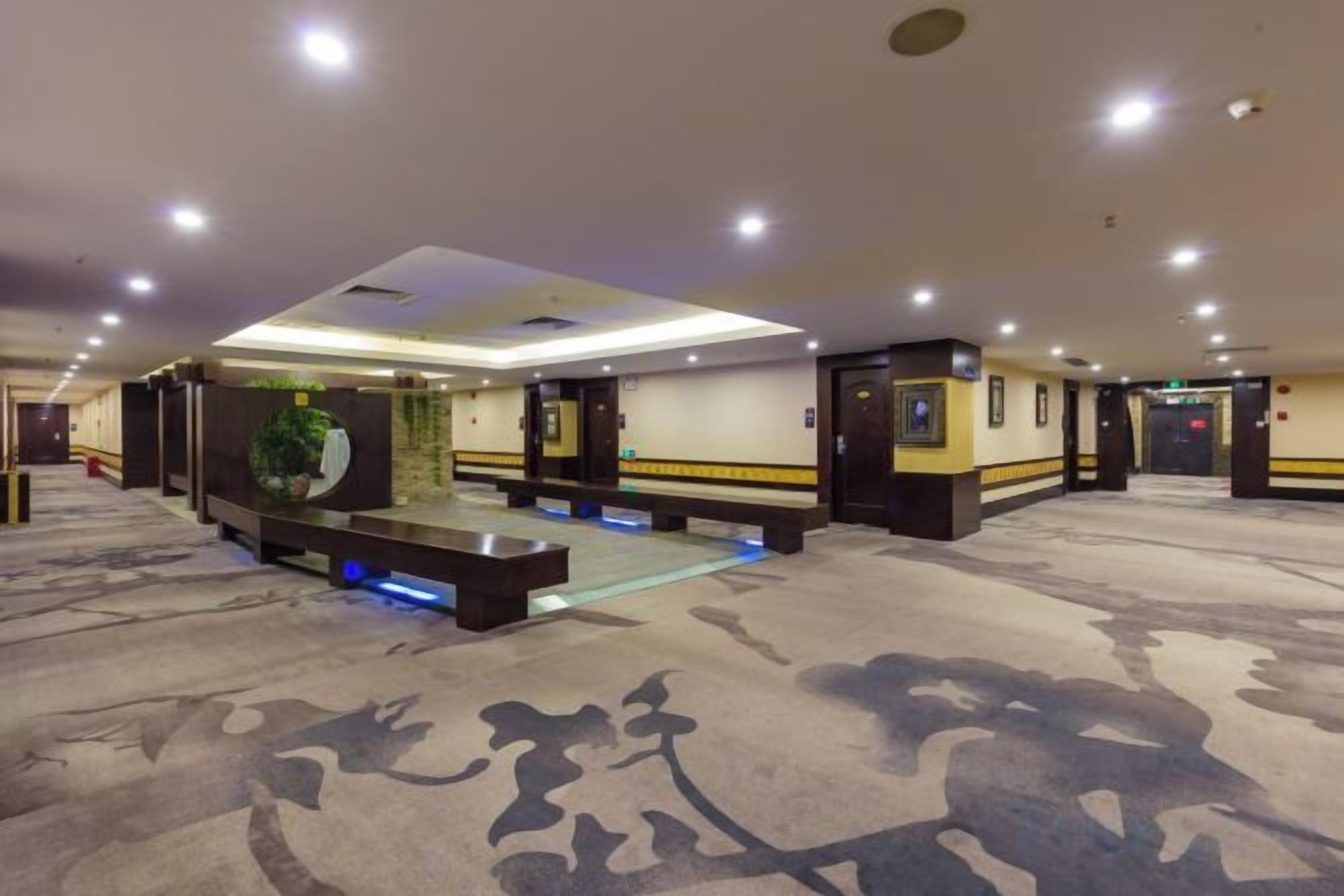 A hotel lobby with a carpeted floor, a reception desk, and a seating area.