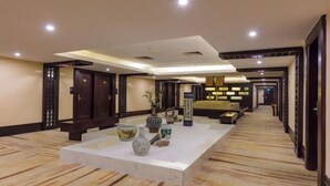 A hotel lobby with a marble reception desk, decorative vases, and a carpeted floor. - Jin Yu Hotel (Zhuhai Gongbei Port Pedestrian Street) (Zhuhai)