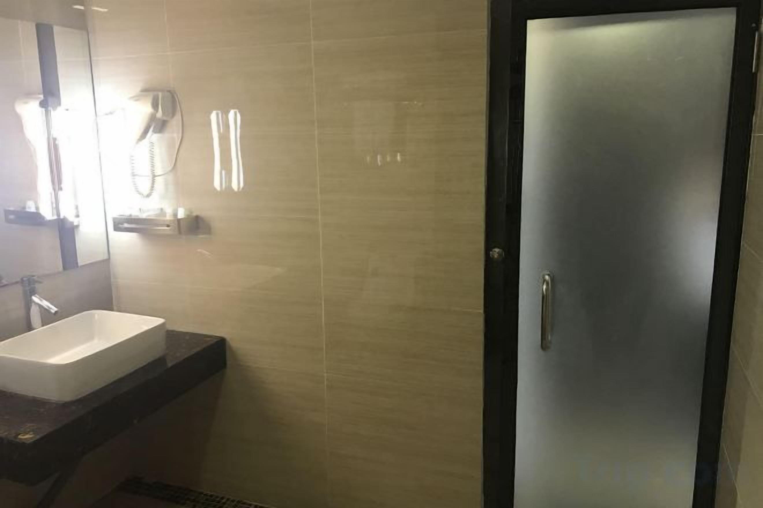 A bathroom with a sink, mirror, and a door.
