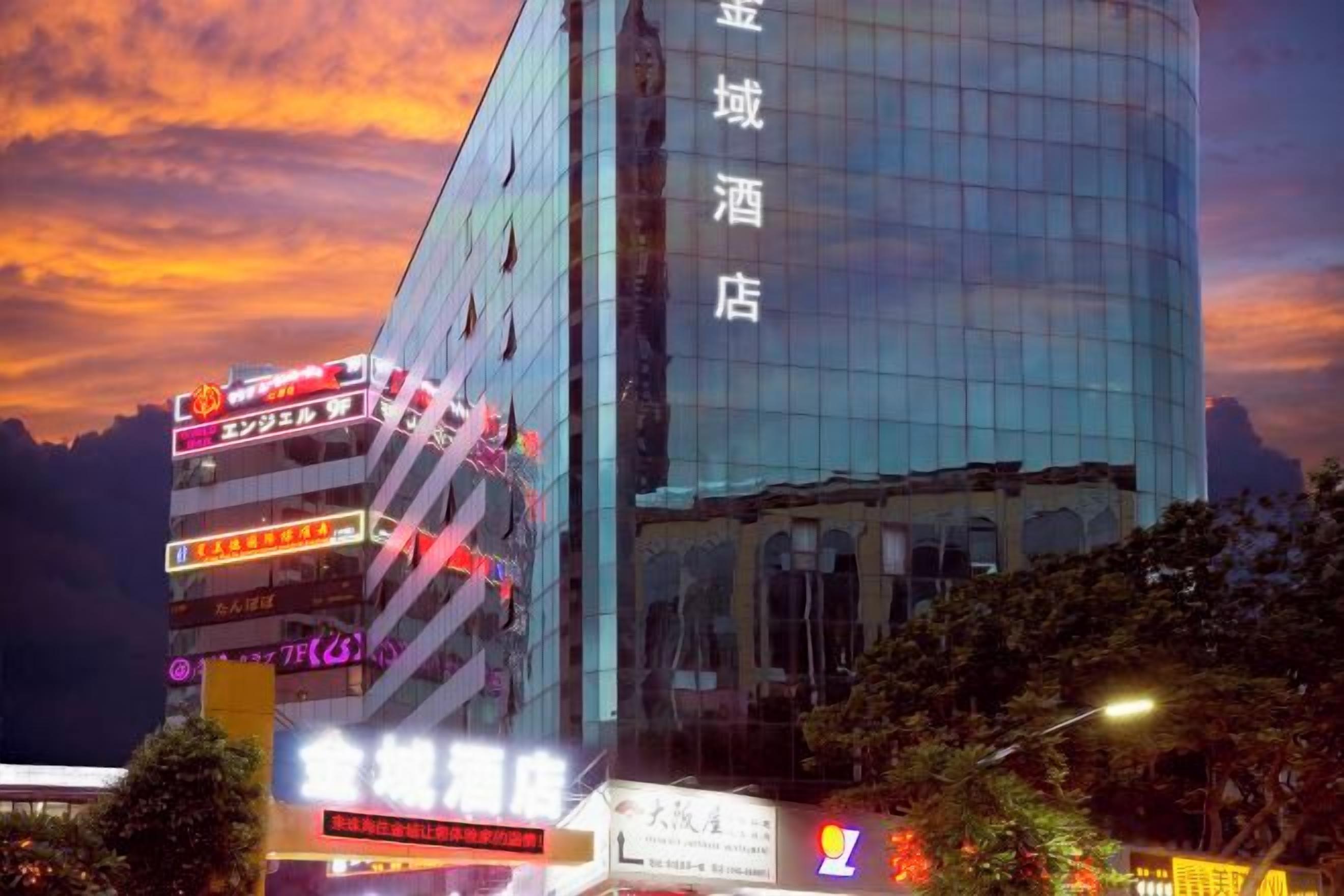 A modern hotel with a glass facade and multiple signs indicating various amenities and services.