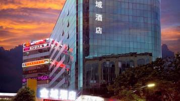 A modern hotel with a glass facade and multiple signs indicating various amenities and services.