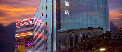 A modern hotel with a glass facade and multiple signs indicating various amenities and services.