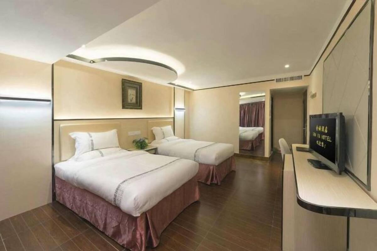 Habitación de hotel con dos camas, un escritorio, televisión y un espejo.