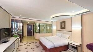 A hotel room with a bed, bedside table, TV, and a bathroom with a glass shower enclosure. - Jin Yu Hotel (Zhuhai Gongbei Port Pedestrian Street) (Zhuhai)