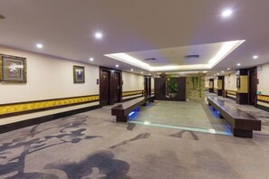 A hotel corridor with a central seating area, doors on both sides, and a patterned carpet. - Jin Yu Hotel (Zhuhai Gongbei Port Pedestrian Street) (Zhuhai)