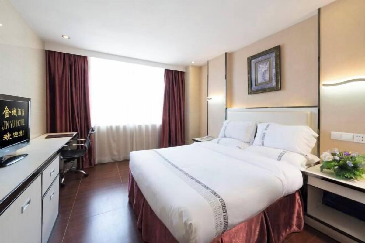 Habitación de hotel con cama, escritorio y ventana con cortinas.